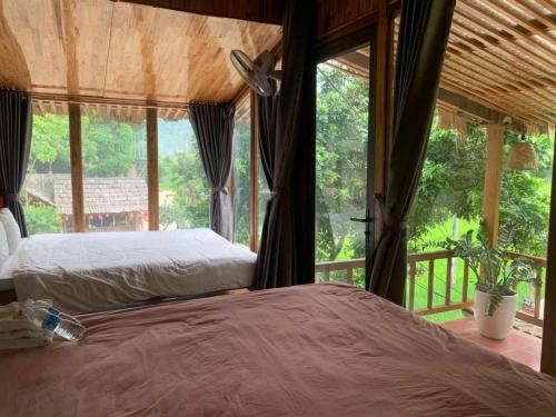 a bedroom with two beds and a large window at Mai Chau Mountain Delight in Mai Châu