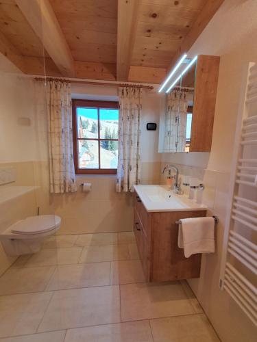 a bathroom with a sink and a toilet and a window at Almchalet Schweigerbuam Lachtal in Hinteralm