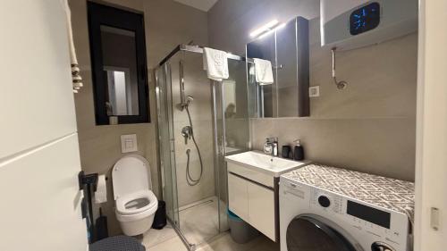 a bathroom with a toilet a sink and a washing machine at Zenith Lux Apartment Beachfront & Parking in Bijela