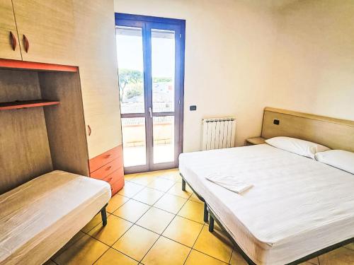 a bedroom with two beds and a door to a balcony at Apartment Mairen-3 by Interhome in Rosolina Mare
