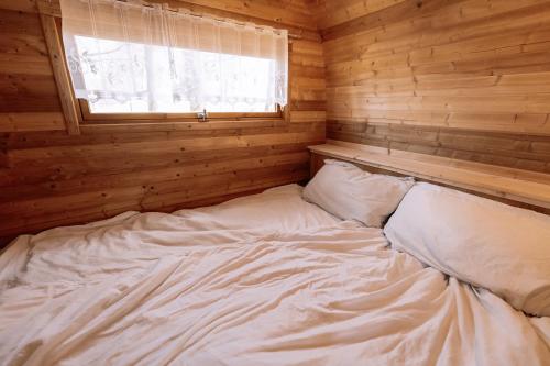 a large white bed in a wooden room with a window at Schlaffass direkt am See in Heideblick