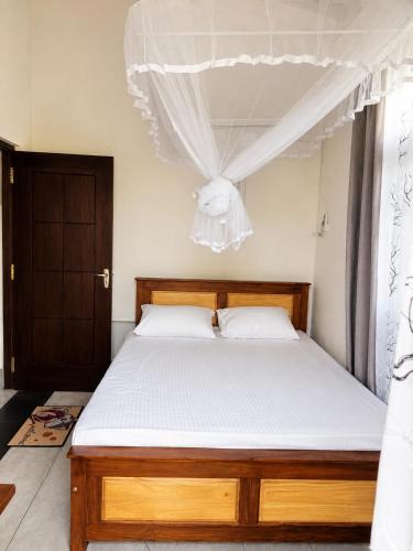 a bedroom with a wooden bed with white sheets at Sunrise Eco Resort in Matara