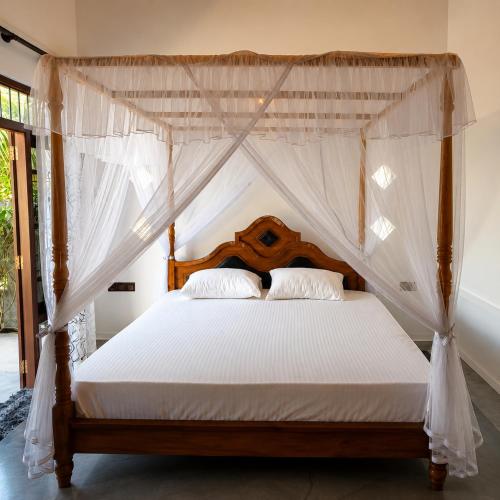 a bedroom with a canopy bed with white sheets and pillows at Sunrise Eco Resort in Matara