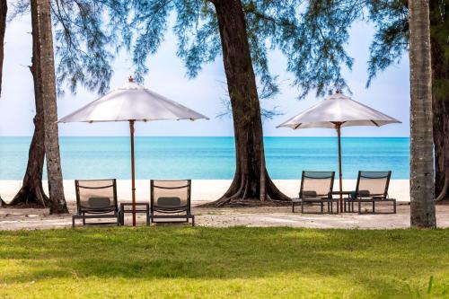 a group of chairs and umbrellas on the beach at OUTRIGGER Khao Lak Beach Resort in Khao Lak