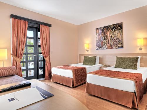 a hotel room with two beds and a desk at Sunrise Resort Hotel in Kizilagac