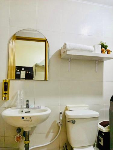 a bathroom with a sink and a toilet and a mirror at Norman Condominium Unit Rental in Dumaguete
