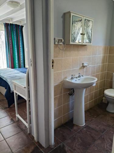 a bathroom with a sink and a toilet and a bed at Sea Wave Cottage in Pearly Beach