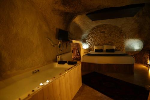 a bedroom with a bed and a tub in a room at Rock Mansion Cappadocia in Nar