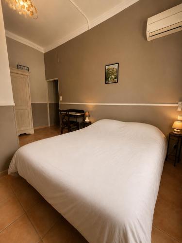 a bedroom with a white bed and a table at Le Grand Hotel Restaurant in Aups