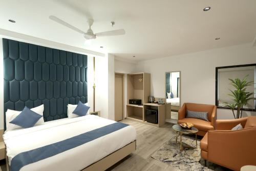 a hotel room with a bed and a chair at Hotel Midtown in Surat