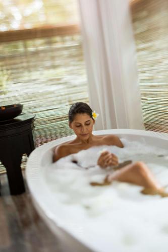 a woman sitting in a bath tub with a baby at Outrigger Mauritius Beach Resort in Bel Ombre