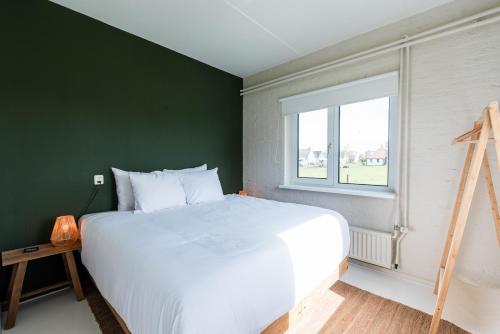 a bedroom with a white bed and a green wall at Strandweg Appartement in Buren