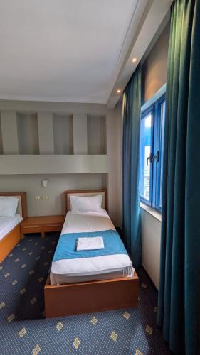a small bedroom with two beds and a window at BAR RESTORANT HOTEL ALPET Elbasan in Elbasan