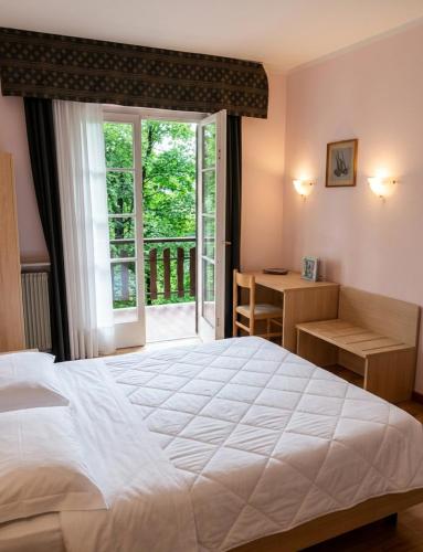 a bedroom with a large white bed and a window at Hotel Paolino in Cavareno
