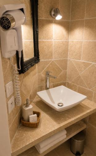 a bathroom with a sink and a hair dryer on a counter at Le Grand Hotel Restaurant in Aups