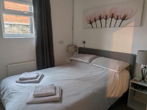 a bedroom with a white bed with towels on it at Sandham Hall Cottage in Sandown