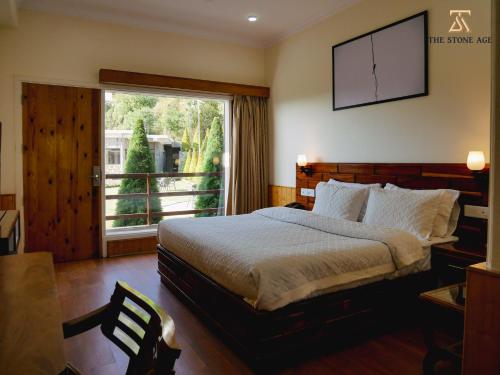 a bedroom with a bed and a large window at The Stone Age : a boutique hotel in Shimla