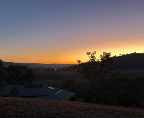 ein Sonnenuntergang über einem Haus auf einem Feld in der Unterkunft Someplace Else in Bonnie Doon