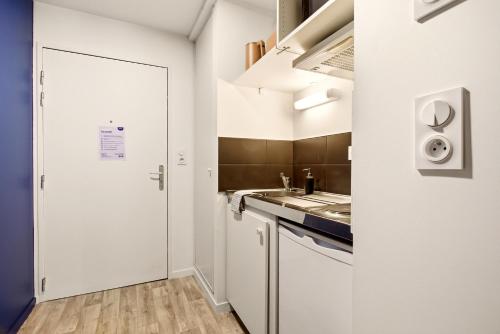 a small kitchen with white cabinets and a sink at Studio L'Indigo - F1 design, hypercentre - CAEN in Caen