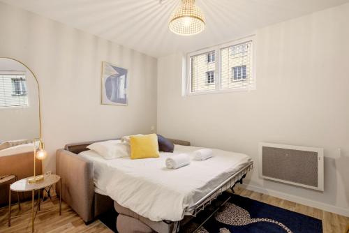 a bedroom with a bed with white sheets and yellow pillows at Studio L'Indigo - F1 design, hypercentre - CAEN in Caen