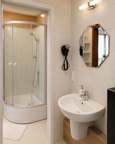 a bathroom with a shower and a sink and a mirror at Willa Celina in Karpacz