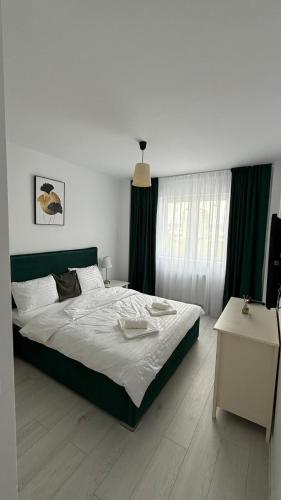 a bedroom with a large bed with green curtains at Apartament Luna in Şelimbăr