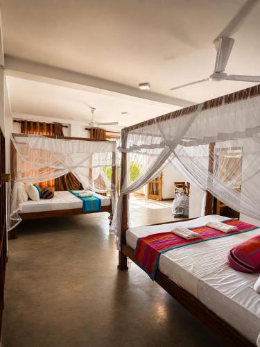 a room with three beds in it with curtains at Kabalana Surf Hostel in Ahangama