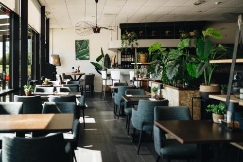 a restaurant with tables and chairs and plants at Resort Land & Zee in Scharendijke