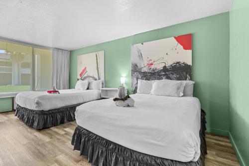 two large beds in a room with green walls at Disney Studio 2 Queens & Shuttle in Kissimmee