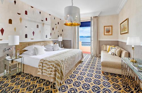a hotel room with a bed and a couch at Hôtel Belles Rives in Juan-les-Pins
