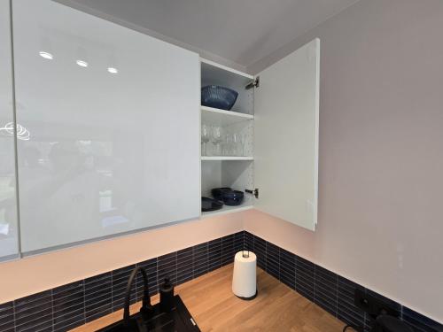 a kitchen with white cabinets and black tiles at Apartamenty Miku - Łeba in Żarnowska