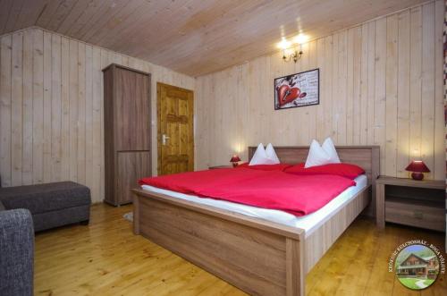 a bedroom with a large bed with a red blanket at Krókusz Kulcsosház - Boga in Boga