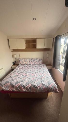 a bedroom with a bed with a quilt on it at Lyons Robin Hood Hazel Park 6 in Rhyl