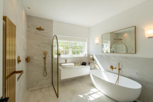 a bathroom with a tub and a sink and a mirror at Sea Estate House in Littlehampton