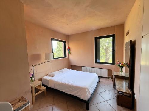 a bedroom with a white bed and two windows at Olive House Galaxidi in Galaxidi