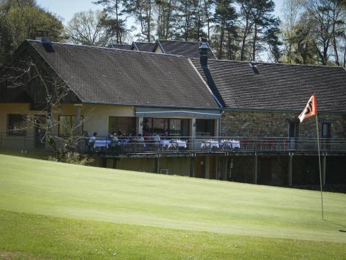 a house with a flag on a golf course at Chambres de séjour et Brasserie du Coiroux in Aubazines