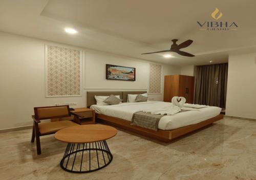 a bedroom with a bed and a table and a couch at Hotel Vibha Grand in Karīmnagar