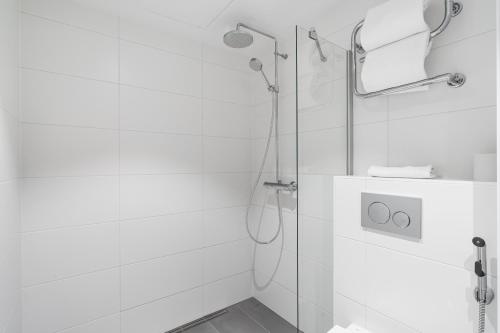 a white bathroom with a shower with a glass door at Omena Hotel Jyväskylä in Jyväskylä
