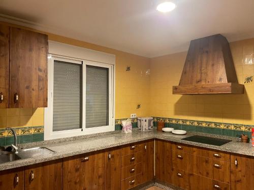 a kitchen with wooden cabinets and a sink and a window at Villa rural en Marchena in Marchena