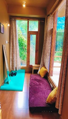 a room with a purple bed in front of a window at Celestia Riverside Retreat in Manāli