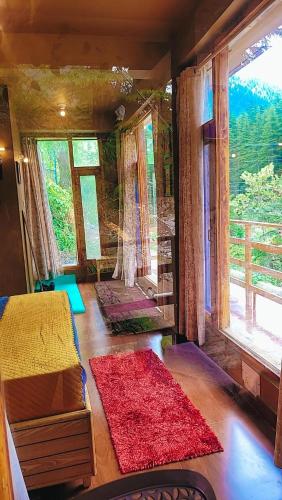 a room with a bed and a large window at Celestia Riverside Retreat in Manāli