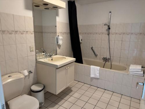 a bathroom with a toilet and a sink and a tub at Hotel Mayflower in Leiden