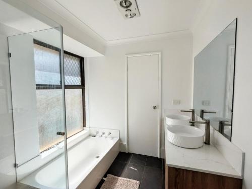 a bathroom with a tub and a sink and a toilet at 3-Bed home with large backyard in Mandurah