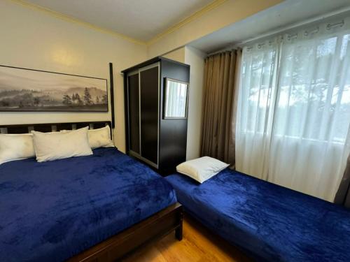 a bedroom with two beds with blue sheets and a window at Condotels at Albergo Hotel Baguio in Baguio