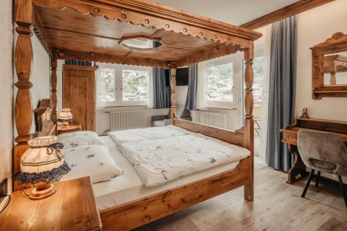a bedroom with a wooden canopy bed and a table at Garni Toni in Ortisei