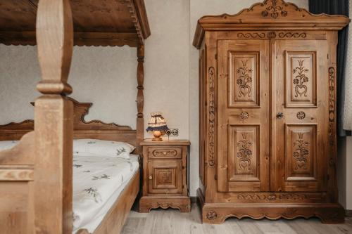 a bedroom with a canopy bed and a wooden cabinet at Garni Toni in Ortisei