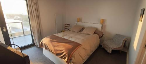 ein Schlafzimmer mit einem Bett, einem Stuhl und einem Fenster in der Unterkunft Appartement neuf avec balcon - Vue mer - Crozon in Crozon