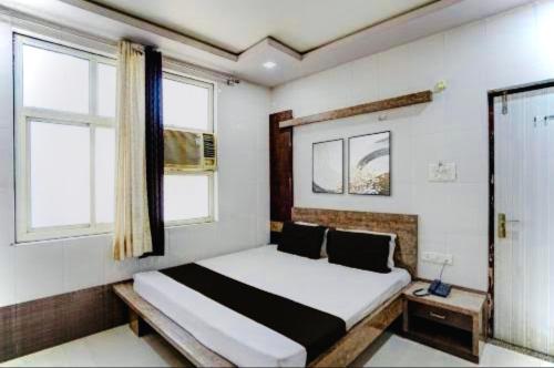 a bedroom with a bed and two windows at Hotel Haji Ali - Sahil inn in Ajmer