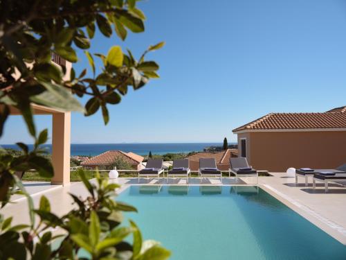 a swimming pool with chairs and the ocean in the background at St John Villas Zakynthos in Tsilivi