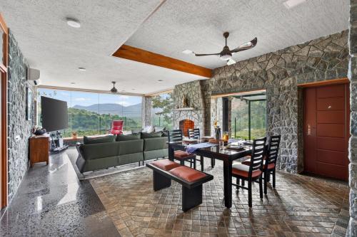 a living room with a table and chairs at SaffronStays Blooming Stone in Kotagiri
